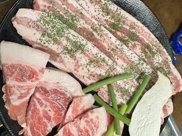 허브가 뿌려진 삼겹살과 다양한 부위의 고기가 준비되어 있다.