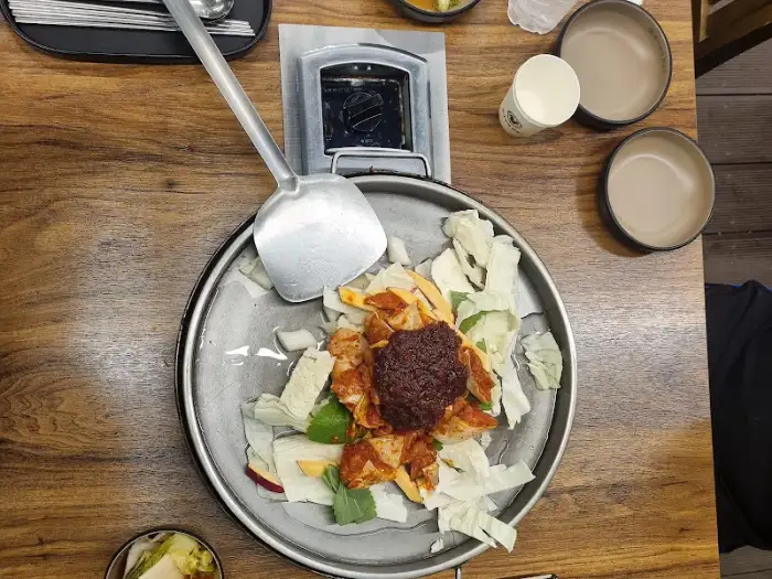 철판 위에 닭갈비 재료가 올려진 모습, 신선한 채소와 양념이 보기 좋다.