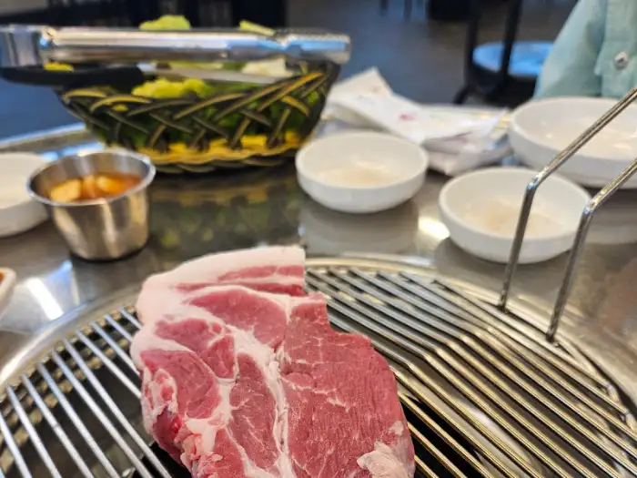 한 덩어리의 신선한 흑돼지 목살이 불판 앞에 놓여 있다.