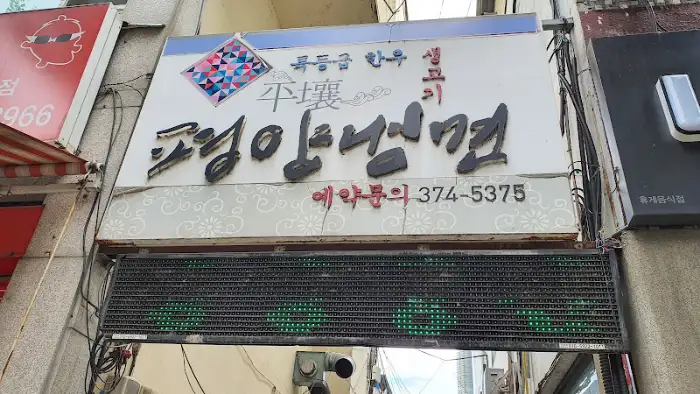 식당 건물 외벽에 걸린 큰 간판, '평창정육점'이라는 글씨와 함께 한우, 흑돼지 등의 메뉴가 보인다.