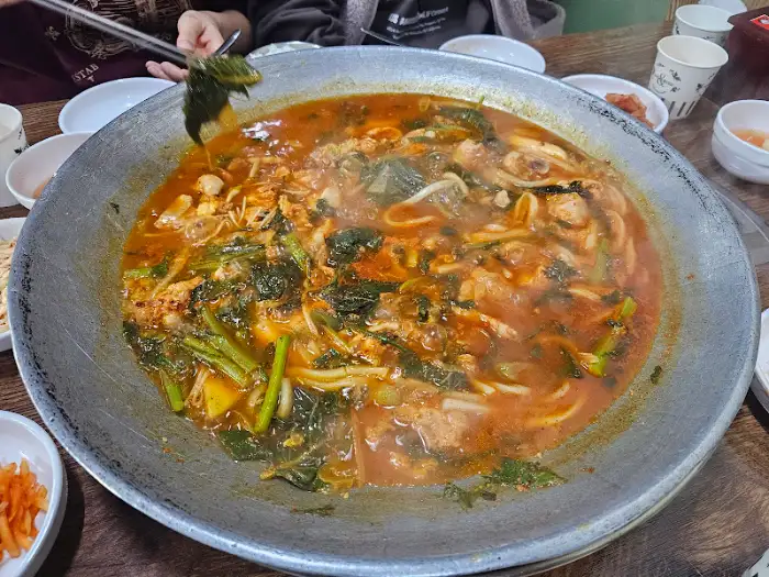 완성된 물닭갈비 국물을 한 숟가락 떠내는 모습
