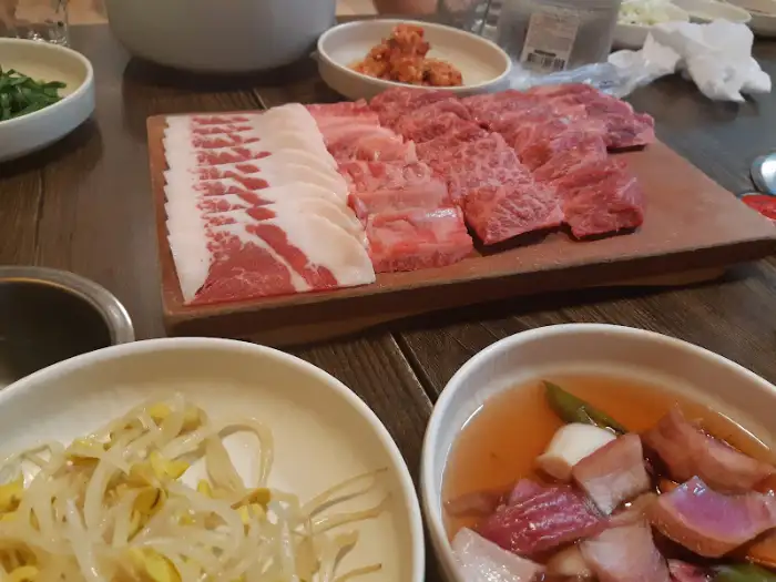 테이블 위에 놓인 숯불과 한우 구이, 그리고 밑반찬들