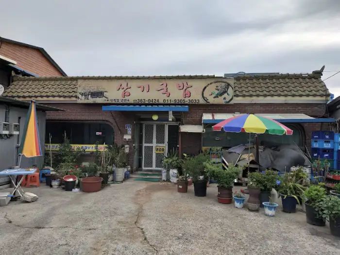 정갈하게 차려진 암뽕순대국밥 한 상. 뚝배기 국물과 함께 다양한 반찬들이 보인다.