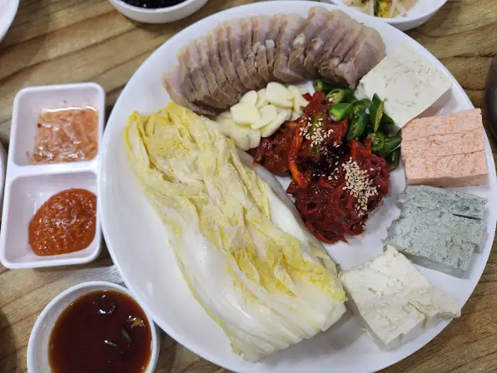 수육, 삼색 두부, 쌈채소, 곁들임 양념 등이 플레이팅된 모습. 다른 각도에서 촬영