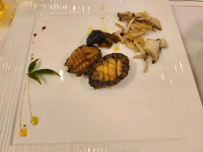 구운 전복과 버섯, 그리고 푸른 잎으로 장식된 요리. 고급스러운 느낌을 줍니다.
