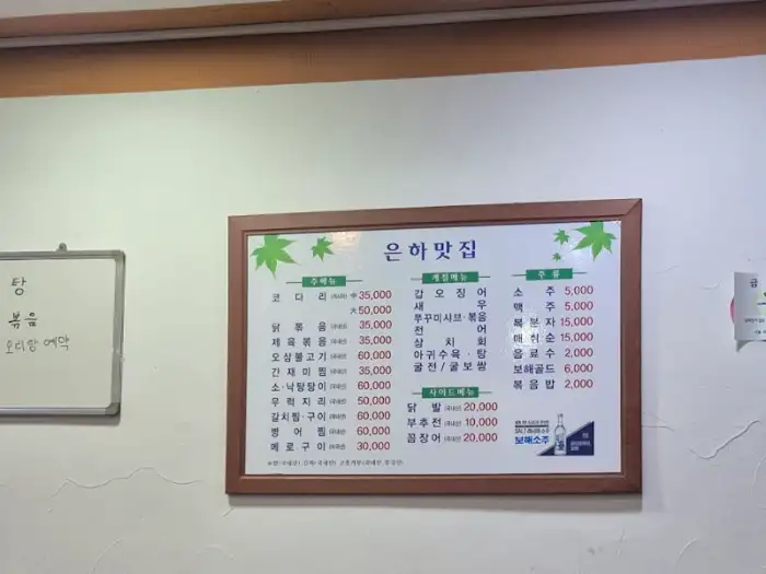 벽에 걸린 메뉴판. 다양한 해산물 요리와 식사 메뉴가 보인다.