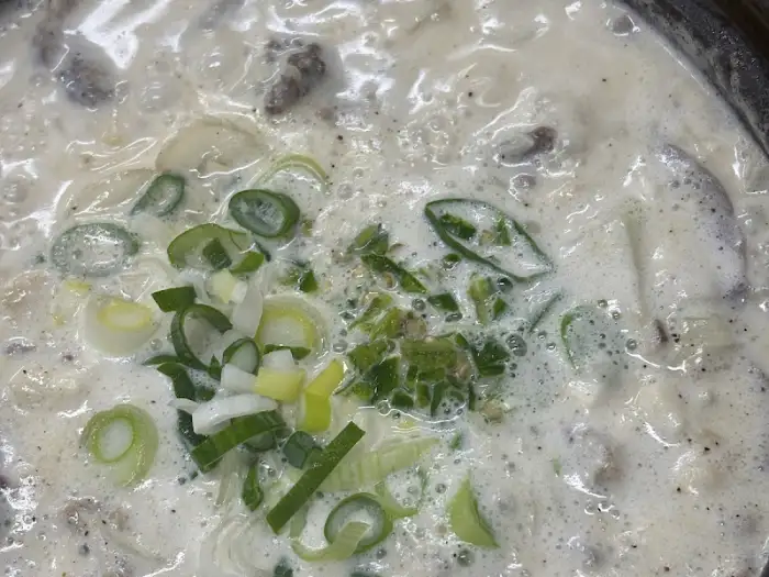 크림 순대국을 클로즈업한 사진. 부드러운 국물과 초록색 파가 돋보인다.