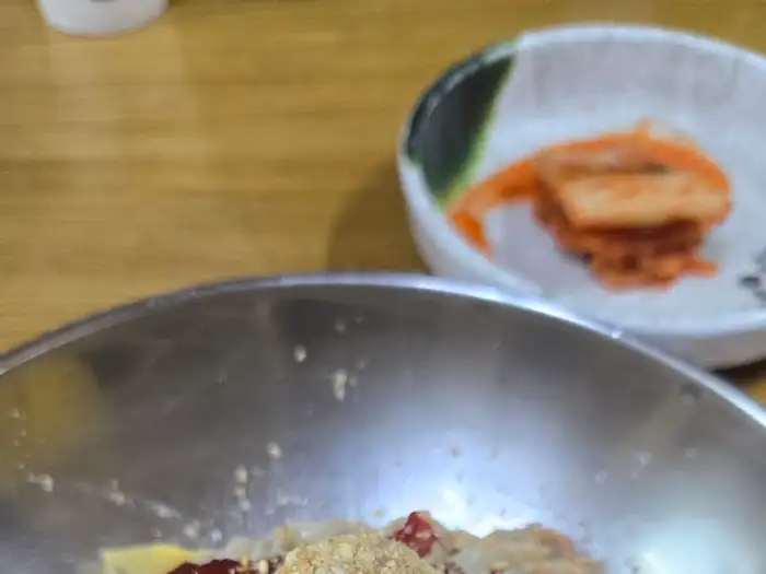 접시에 담긴 김치의 모습과 함께, 멀리 막국수 그릇이 보인다.