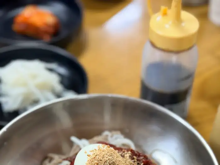 막국수 그릇의 윗부분이 클로즈업된 사진으로, 계란과 양념, 고명이 보인다.