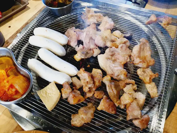 숯불 위에서 익어가는 꼬치구이와 곁들임 반찬