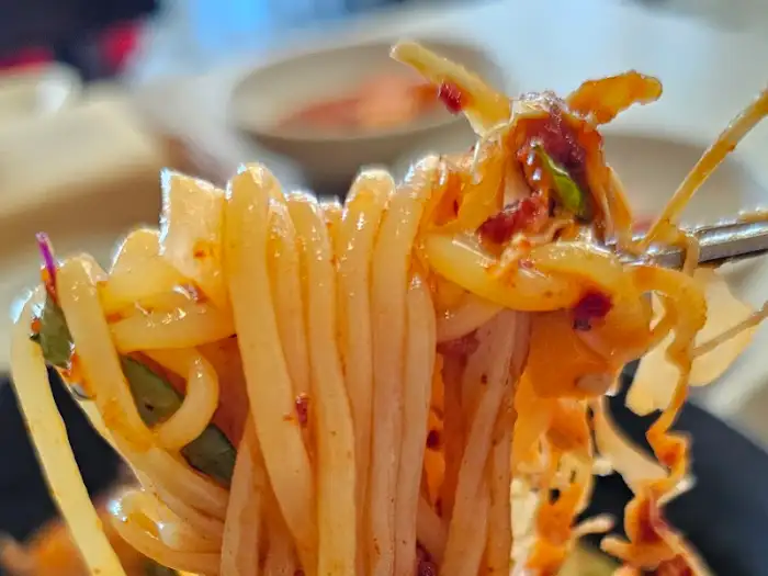 포크에 돌돌 말린 비빔국수. 양념이 면발에 진하게 배어 있는 모습이 보인다.