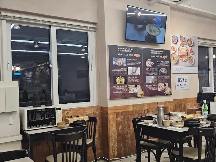 식당 내부 모습. 테이블과 벽면 메뉴판, 창밖 풍경 등이 보인다.
