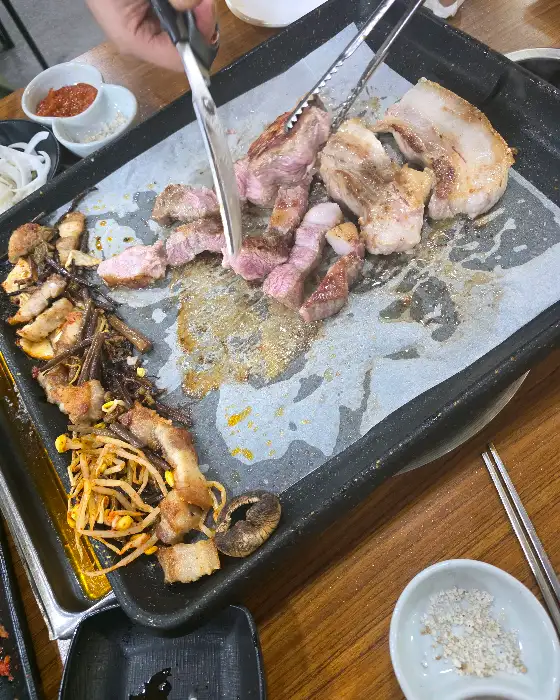 집게와 가위로 고기를 자르고 있는 손