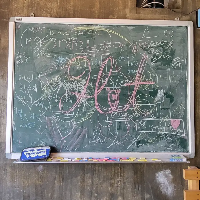 칠판에 낙서가 가득한 모습, 방문객들이 자유롭게 그림을 그리고 글씨를 남긴 흔적이다.