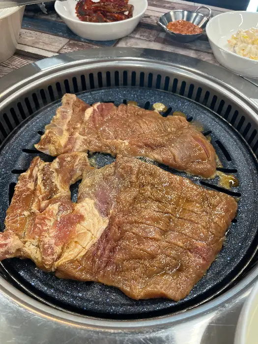 숯불 위에 올라간 먹음직스러운 돼지갈비. 양념이 고르게 배어 있고, 숯불 향을 머금고 있습니다.