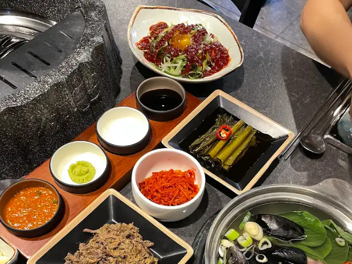 다양한 밑반찬과 소스, 육회로 보이는 요리