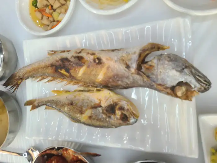 잘 구워진 민어와 조기 두 마리가 먹음직스럽게 담겨 있습니다.