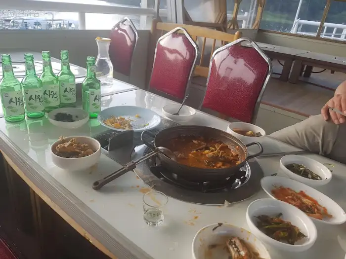 테이블에 차려진 매운탕과 밑반찬, 소주병