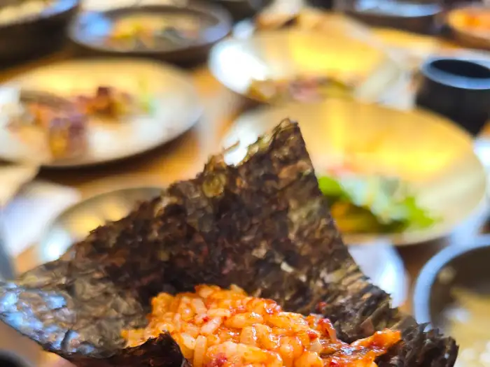 김에 밥과 양념게장을 싸서 먹는 모습