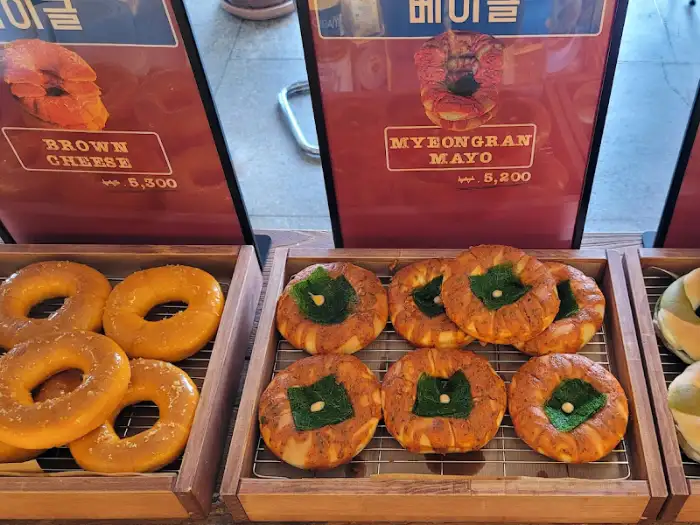 두 가지 종류의 베이글이 나란히 진열되어 있는 모습. 하나는 브라운 치즈가 뿌려져 있고, 다른 하나는 야채가 곁들여져 있다.