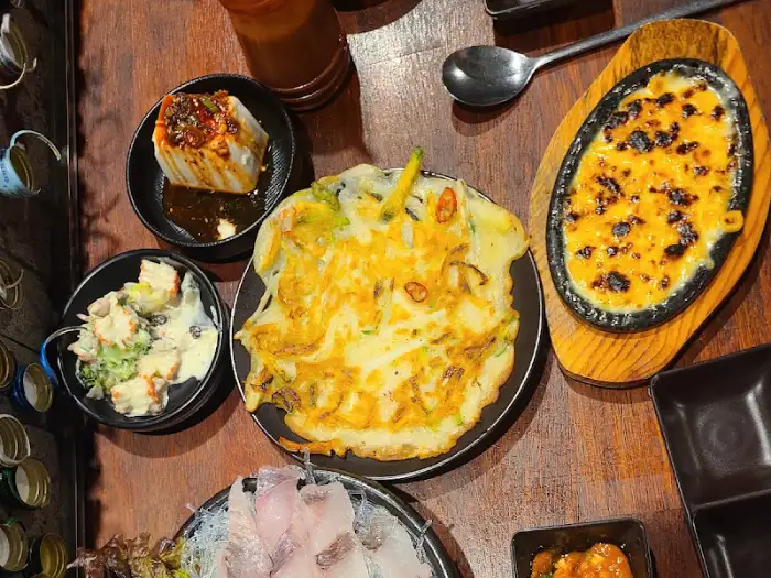 다양한 종류의 맛있는 음식들이 테이블 위에 가득 차려져 있습니다.