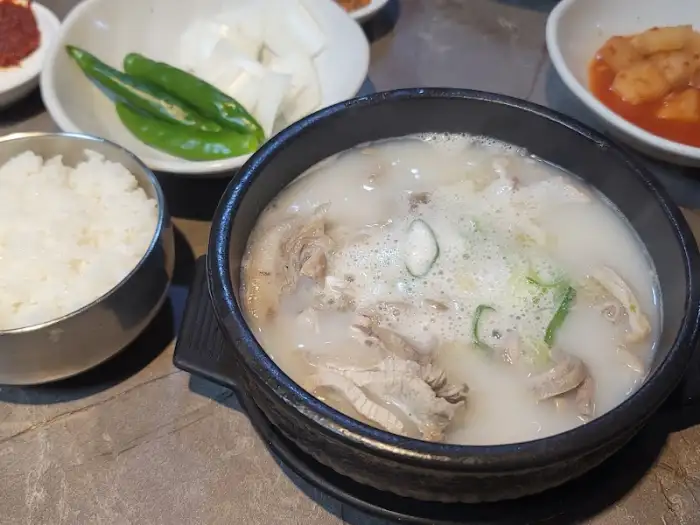 뽀얗고 진한 순대국밥 한 그릇과 밥, 김치, 고추가 담긴 접시