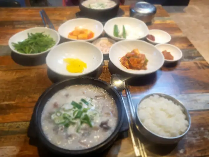 테이블 위에 차려진 순대국밥, 밥, 그리고 여러 종류의 밑반찬
