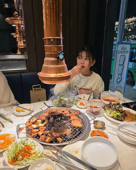 불판 위에서 구워지고 있는 돼지갈비와 식사 중인 손님
