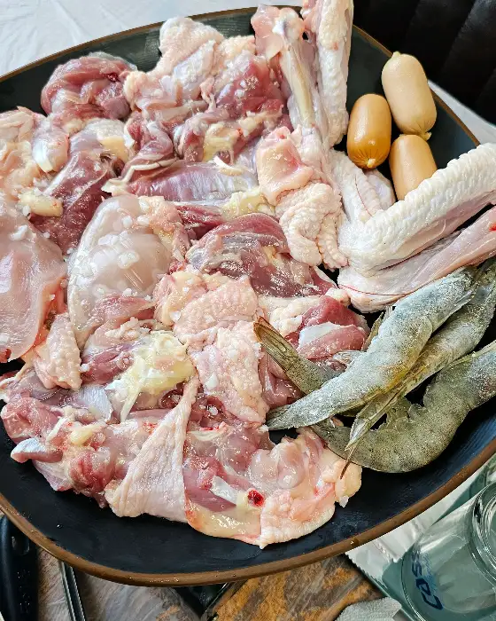 다양한 부위의 신선한 닭고기와 새우, 소시지가 담긴 접시