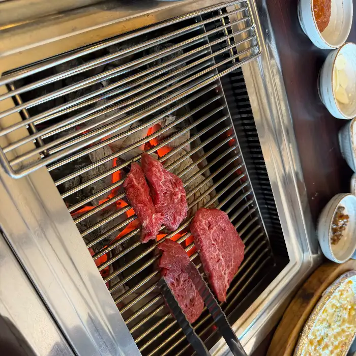 숯불 위에서 구워지고 있는 소고기와 함께 차려진 밑반찬들