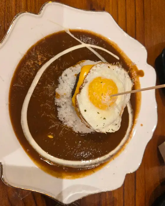 카레 소스 위에 밥, 그 위에 함박 스테이크와 계란 후라이가 올라간 비주얼