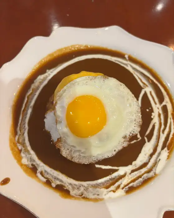 카레 소스 위 밥, 그 위에 함박 스테이크와 반숙 계란 후라이가 올라간 모습