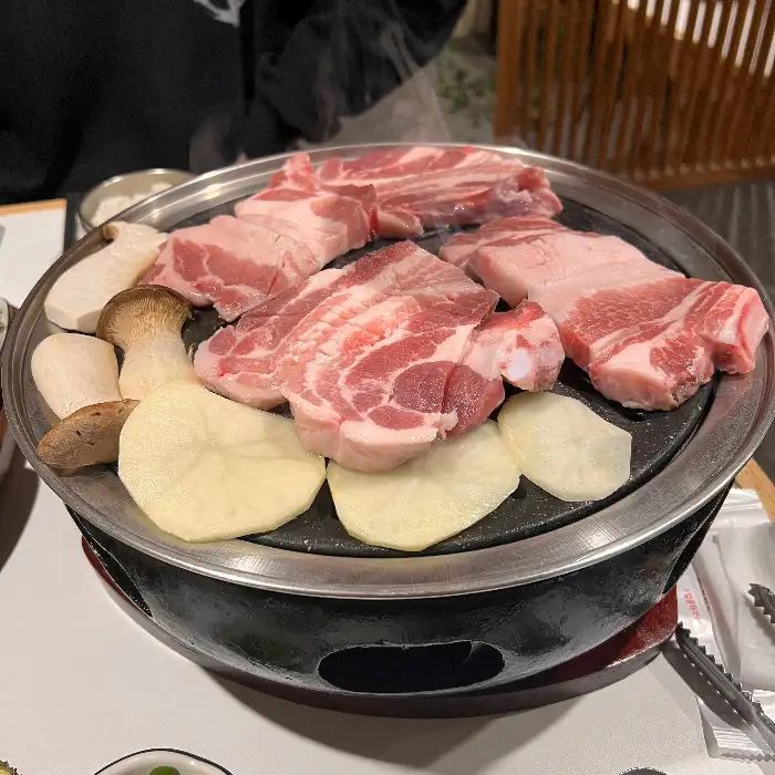 불판 위에 올라가기 전 신선한 삼겹살과 목살, 버섯, 감자 슬라이스