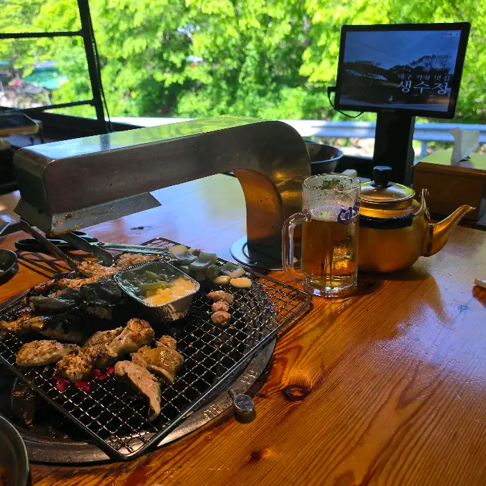 야외 테이블에서 보이는 푸르른 녹음과 함께 맥주 한 잔
