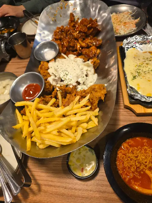 치킨, 샐러드, 감자튀김, 콘치즈 등이 차려진 식탁