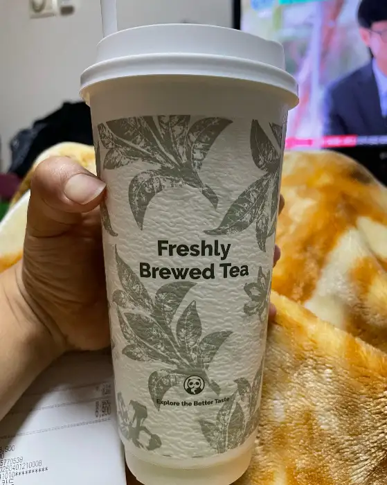 깔끔한 디자인의 테이크아웃 컵에 'Freshly Brewed Tea'라고 적혀 있습니다.