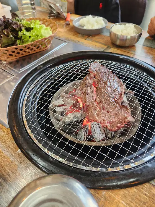 숯불 위에서 익어가는 두툼한 고기 한 점