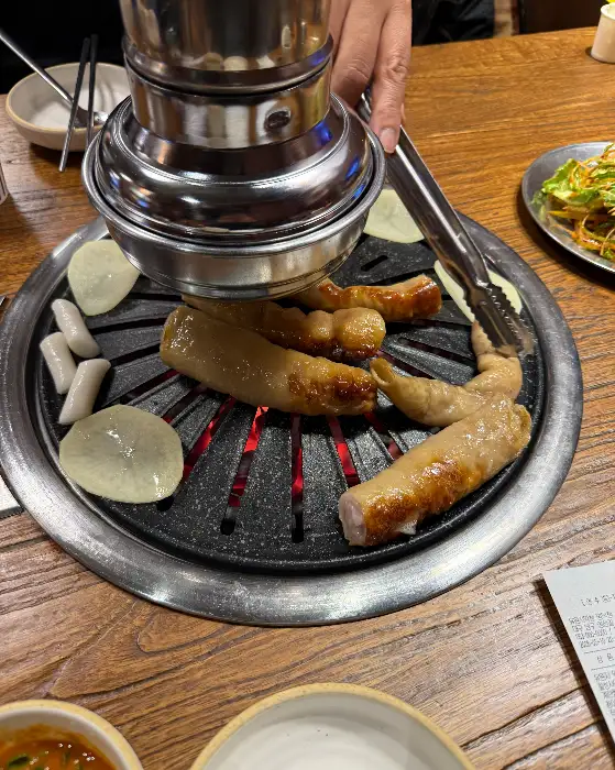 불판 위에서 익어가는 막창과 곁들임 메뉴