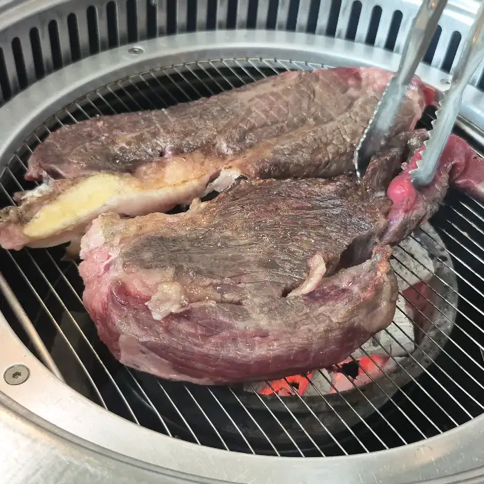 집게로 익고 있는 두툼한 한우를 옮기는 모습