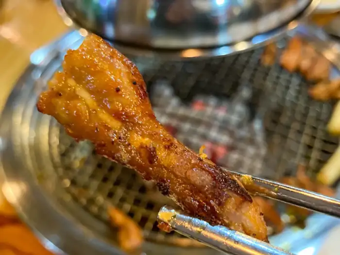 집게로 집어 올린 숯불 닭갈비