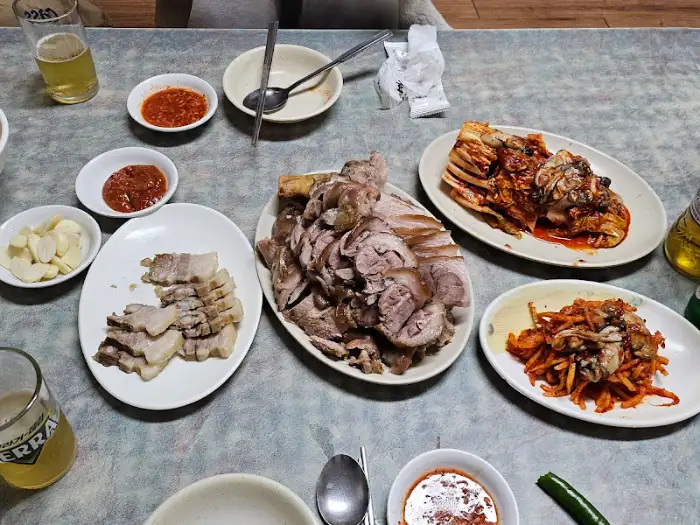 테이블에 차려진 푸짐한 족발, 보쌈, 김치, 비빔국수 등의 음식들