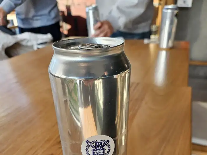 크롬 색상의 맥주 캔이 테이블 위에 놓여 있다.