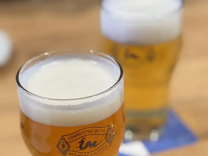 맥주가 담긴 투명한 잔, 잔 안에는 황금빛 맥주와 풍성한 거품이 보인다.