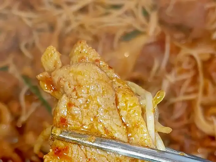 오리 주물럭 한 점을 집게로 집어 올린 모습