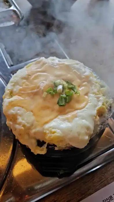 돌솥밥에 계란 노른자를 올리고 비비는 모습