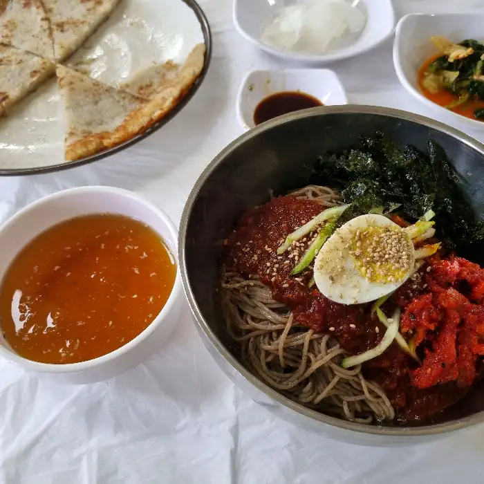 먹음직스럽게 비벼진 비빔막국수와 곁들임 반찬들