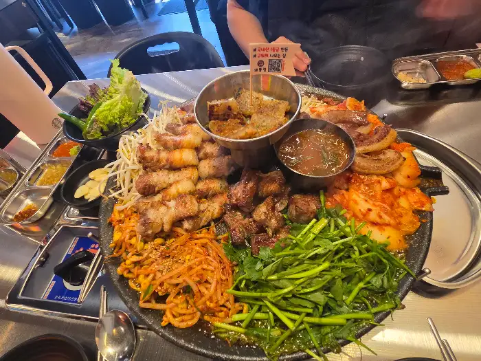 다양한 종류의 고기와 곁들임 채소가 풍성하게 담긴 불판
