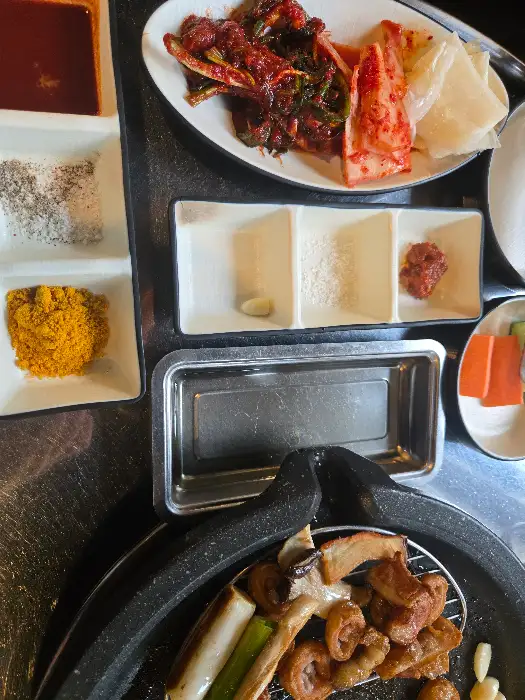다양한 종류의 김치와 쌈장, 마늘 등이 담긴 밑반찬 구성