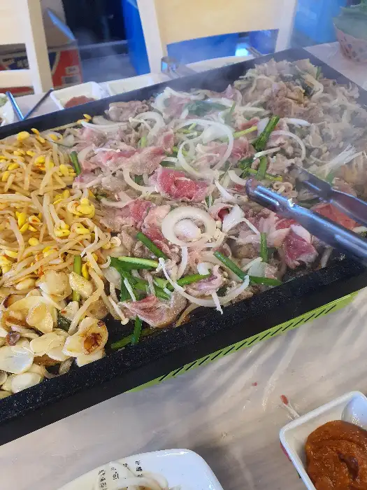 불판 위에 푸짐하게 올라간 오리고기와 채소들