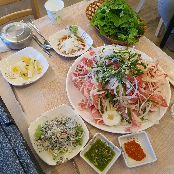 테이블에 차려진 오리불고기와 쌈 채소, 밑반찬들